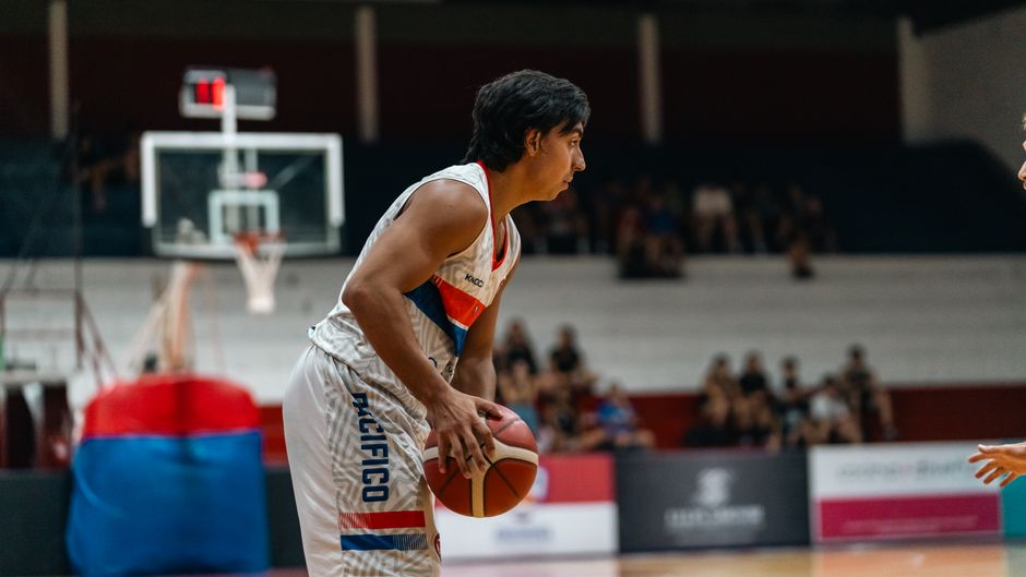 Focused basketball player in an indoor gym ready to pass the ball during a match.
